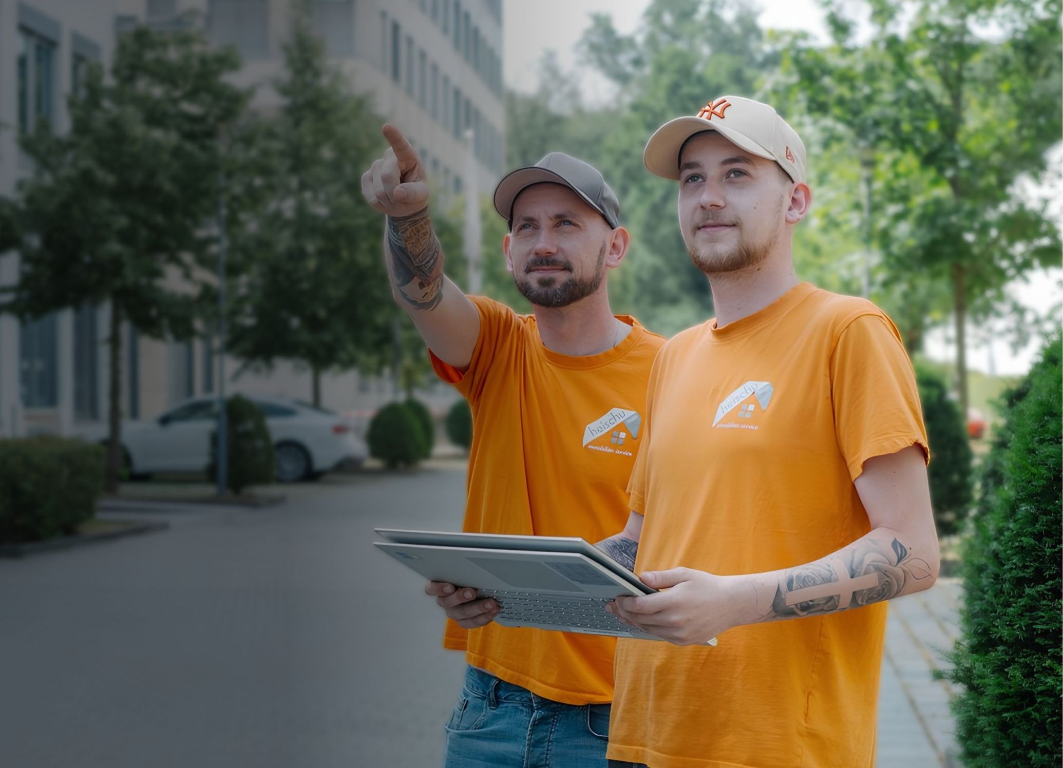 Zwei Mitarbeiter mit einem Laptop zeigen auf etwas in der Ferne